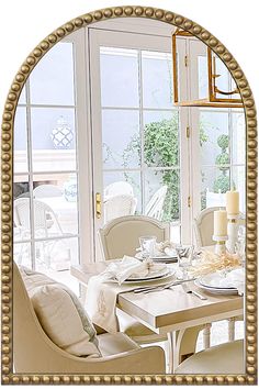 a dining room table set for two with white chairs and gold trim around the edges