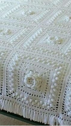 a white crocheted bedspread with flowers on it