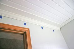 some blue tape is taped to the ceiling above a mirror and door in a room with white walls