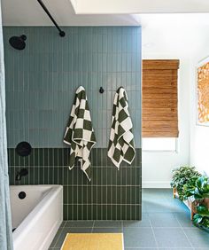 two black and white towels hanging on the wall next to a bathtub in a bathroom