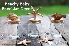 three small glass jars with gold fish and starfish in them on a wooden table