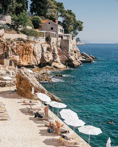 the beach is lined with umbrellas and lounge chairs near the water's edge