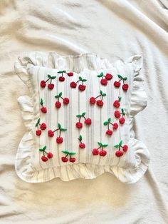 an embroidered pillow with cherries on it