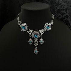 "This romantic necklace features richly detailed antiqued silver filigrees, scrolls and beaded accents. Adorned with sparkling dark aqua glass crystals, its breath taking design will add Victorian elegance to your outfits. Decorated portion is 8 1/4\" wide and 2 3/4\" tall in the very center.  Necklace length is adjustable with soldered stainless steel cable chain, lobster clasp and extender. If you would like a different length, please send us a message. Matching headpiece and earrings are listed separately in our store. If you don't see items with a color you want, feel free to ask about availability." Ornate Silver Beaded Jewelry, Victorian Turquoise Necklace For Wedding, Gothic Filigree Necklace For Wedding, Victorian Turquoise Jewelry For Wedding, Gothic Wedding Necklace With Filigree Detail, Gothic Filigree Wedding Necklace, Ornate Turquoise Jewelry For Wedding, Ornate Blue Necklace With Intricate Design, Ornate Bridal Necklace With Intricate Design