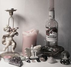 a table topped with bottles and figurines next to a candle