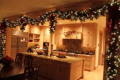 a kitchen decorated for christmas with garland and lights