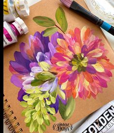 an art project with watercolors and paints on it, including flowers in the middle