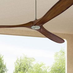 a ceiling fan that is hanging from the ceiling in front of a window with trees outside