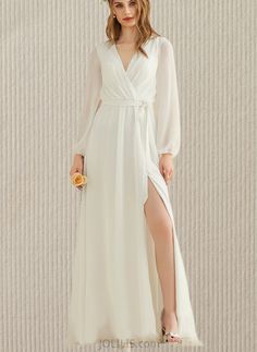 a woman in a long white dress with a slit on the leg and a flower in her hair