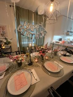 a table set for a birthday party with plates and silverware, candles and decorations