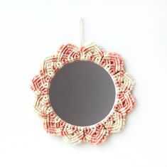 a round mirror hanging on the wall with beaded trim around it's edge