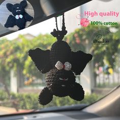 a crocheted teddy bear hanging from a car's dashboard window with the words high quality 100 % cotton written on it