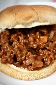 a sandwich with meat and onions on a white plate