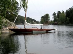 a sailboat floating on top of a lake next to a shore line with trees