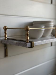 bowls are sitting on a shelf in a kitchen with brass fixtures and marble counter tops