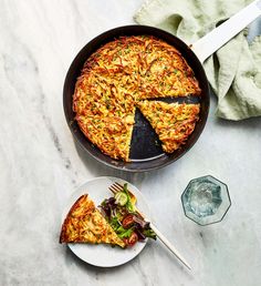 a pizza pie sitting on top of a pan next to a plate with a slice missing