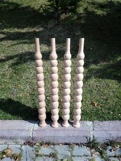 three tall wooden poles sitting on top of a grass covered field next to a sidewalk