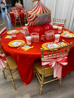 a circus themed birthday party with red and yellow table cloths, striped napkins, gold chairs and plates