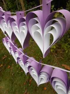 paper hearts hanging from a clothes line in the grass