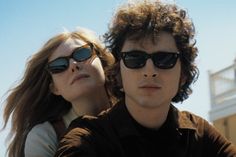 two people wearing sunglasses and one is looking at the camera with his head tilted to the side