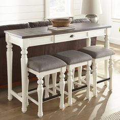 a kitchen table with four stools in front of it and a lamp on the side