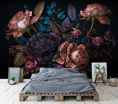 a bed sitting in front of a black wall with flowers on it