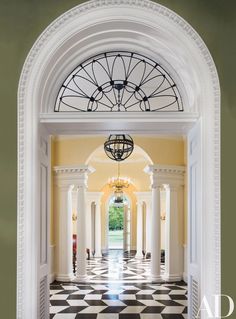 an archway leading into a hallway with columns and chandelier