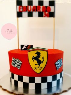 a red cake with black and white checkered design on the top has a ferrari logo