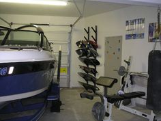 there is a boat in the garage next to a gym equipment rack and exercise bench