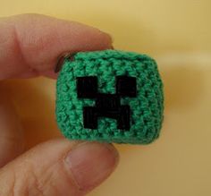 a hand holding a small green crocheted object