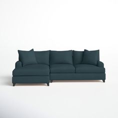 a blue sectional couch with pillows on the top and bottom, sitting in front of a white wall