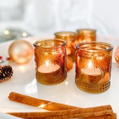 some candles are sitting on a plate next to christmas ornaments and pineconi cones