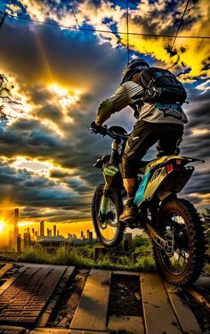 a man riding a dirt bike on top of a wooden platform under a cloudy sky