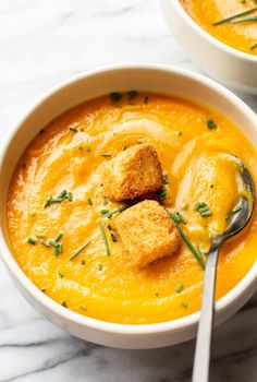 two bowls of soup with croutons in them