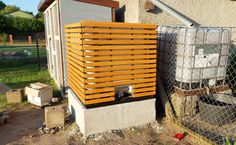 a wooden box sitting on the side of a building next to a fenced in area