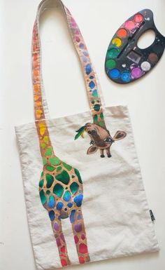 a tote bag with a giraffe painted on it next to a paintbrush