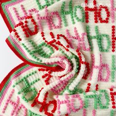 a crocheted blanket with red, green and pink letters on it's edges