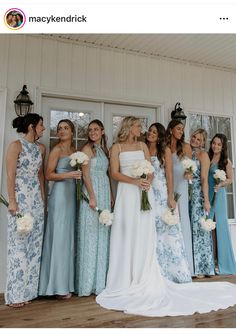 a group of women standing next to each other in front of a white building holding bouquets