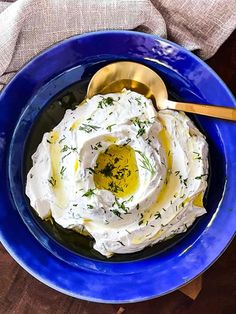 a blue bowl filled with whipped cream and herbs