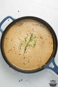 a pot filled with soup sitting on top of a white counter next to a blue spatula