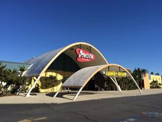 the entrance to a fast food restaurant under a blue sky with palm trees in the background