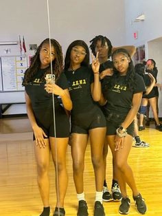 four girls in black shirts and shorts standing on a basketball court