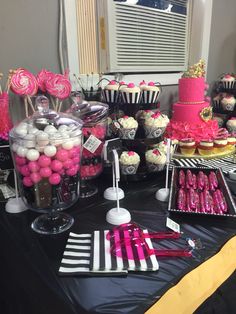 a table topped with lots of cupcakes and candy bar items on top of a black table cloth