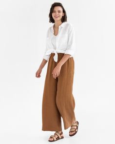 "Upgrade your look with ALCUDIA wide leg linen pants in Cinnamon. These high-rise pants have a stylish wide leg and hit below the ankle (28.5\"/72 cm inseam). They're both fashionable and functional, with side seam pockets for convenient storage and a flattering elastic waist. Perfect for any occasion. Details: * Wide leg design * 2 side seam pockets for added functionality and style * High rise and elastic waist for a flattering fit * Medium weight linen (approx. 200 gsm) * The model is wearing Brown Linen Bottoms For Summer, Brown Linen Summer Bottoms, Versatile Linen Wide Leg Summer Pants, Versatile Summer Linen Wide Leg Pants, Summer Brown Linen Bottoms, Chic Flax-colored Relaxed Fit Wide Leg Pants, Brown Linen Wide Leg Pants With Pockets, Chic Wide Leg Pants In Flax With Relaxed Fit, Casual Brown Linen Wide Leg Pants