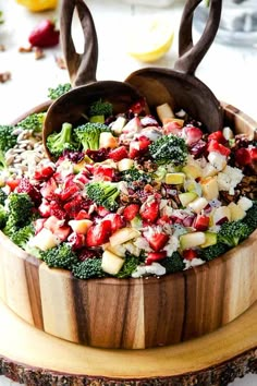 a wooden bowl filled with broccoli, strawberries and other vegetables on top of a table