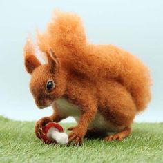 a needle - felt squirrel playing with a ball on the grass