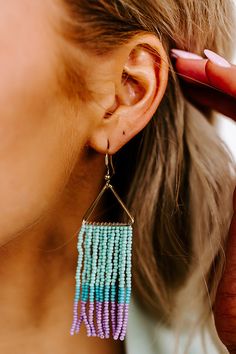 - These adorable earrings are the perfect accessory for a night on the dance floor! - A hook with dangling gold toned triangles and beaded fringe design featuring ocean wave, blue, and purple hued beads - Length: 3.5 inches Purple Dangle Beaded Earrings For Beach, Adjustable Ocean-inspired Earrings For Summer, Blue Fringe Beaded Earrings For Beach, Handmade Ocean-inspired Earrings For Beach Season, Handmade Ocean-inspired Earrings For Beach, On The Dance Floor, Ocean Wave, Beaded Fringe, The Dance