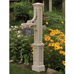 a white mailbox sitting in the middle of a flower garden next to a house