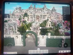 a person holding up a tablet with a large mansion on it's screen,