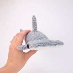 a hand is holding a small knitted toy that looks like a whale's head